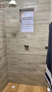 a bathroom with a tiled wall with a window at Quarto Para Dormir Próximo do Aeroporto Gru POUSO RÁPIDO in Guarulhos
