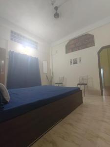 a bedroom with a blue bed in a room with chairs at Nest retreat home stay in Jorhat