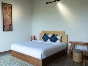 a bedroom with a bed with blue pillows and a table at Aki Eco-villa Hội An in An Bang