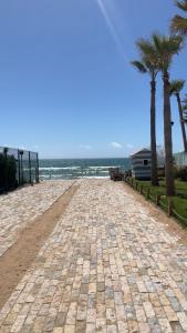 une route pavée à côté de la plage avec des palmiers dans l'établissement Mini-villa Imiouadar vue mer , grand confort, à Agadir