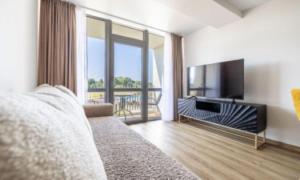 Un dormitorio con una cama y un televisor de pantalla plana. en Šeimos apartamentai, Mano Šventovė, en Palanga