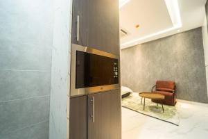 Una sala de estar con un televisor y una silla. en D8/Airport Proximity Comfort, en Otele