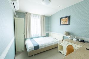 a small bedroom with a bed and a desk and a window at New Osaka Hotel Shinsaibashi in Osaka