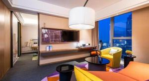 a living room with a couch and a tv at Hampton by Hilton Suzhou XiangCheng in Suzhou