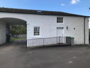 ein weißes Backsteingebäude mit einem Tor davor in der Unterkunft DairyCottage, 5, TELFORD MEWS BEATTOCK in Moffat