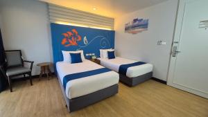 a hotel room with two beds and a chair at Days Inn by Wyndham Patong Beach in Patong Beach