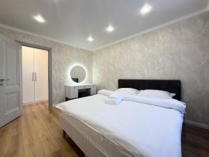 a bedroom with a large white bed and a mirror at Двухкомнатная квартира в центре in Pavlodar