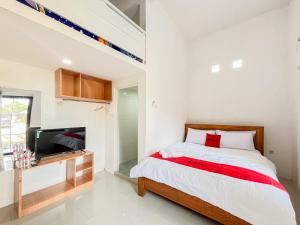 Un dormitorio con una cama y un televisor de pantalla plana. en RedDoorz Syariah at Jl Veteran Kediri, en Kediri