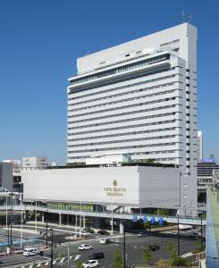 un grande edificio bianco in una città con un parcheggio di Hotel Granvia Hiroshima a Hiroshima