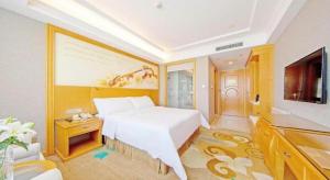 a bedroom with a large white bed and a television at Vienna Hotel Guangdong Zhongshan Ancient Town Haizhou in Zhongshan