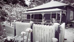 a fence in front of a house covered in snow at Le Petit Chateau in Medlow Bath