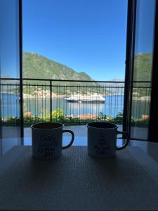 two coffee mugs sitting on a table in front of a window at Stunning Sea View - Brand New Apartments in Kotor