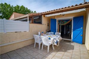 a table and chairs on a patio with blue doors at La Marina in Saint-Cyprien-Plage