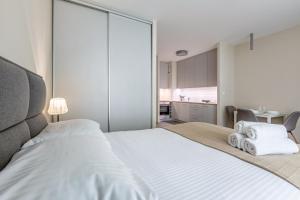 Un dormitorio con una gran cama blanca y una cocina. en Wola Studio Nest Warszawa by Aparo - Metro Rondo Daszyńskiego, Centrum, Browary Warszawskie, Winda, Balkon, en Varsovia