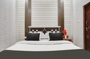 a bedroom with a large white bed with black pillows at EMERGE HOTEl in Hardoī +3 photos