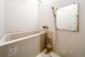 a bathroom with a bath tub and a mirror at Locanda shin-Osaka in Osaka