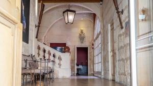 a hallway in a building with a table and chairs at Hôtel Amphithéâtre in Arles