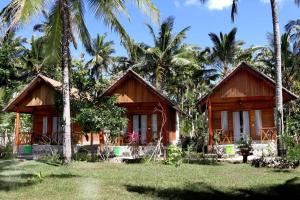 two wooden cottages in front of palm trees at Dangin Kubu Pedoman in Toyapakeh