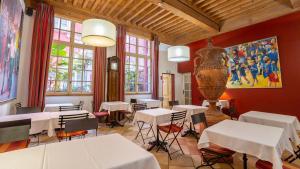 a restaurant with tables and a large vase on the wall at Hôtel Amphithéâtre in Arles