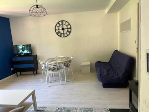 un soggiorno con un tavolo e un orologio a parete di SAVIGNAC a Savignac-les-Ormeaux