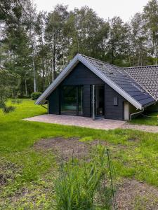 a small black house with glass doors in a yard at Charming A-Frame House Near Gudmindrup Beach in Højby +26 photos
