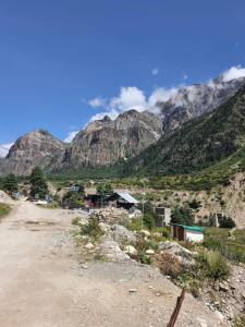 Un pueblo en un camino de tierra con montañas al fondo. en Kailash Mansarovar Homestay, en Garbyāng