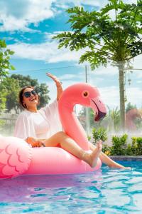 a woman sitting on an inflatable flamingo in a pool at D'svarga Glamping in Seturan
