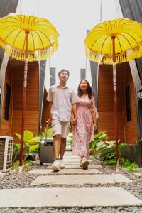 a man and a woman walking under two yellow umbrellas at D'svarga Glamping in Seturan
