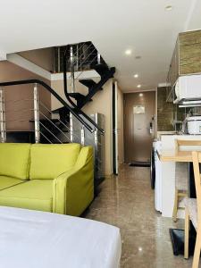 a living room with a yellow couch and a kitchen at Praise Hotel Xujiahui Zikawei Shanghai Stadium 上海徐家汇赞寓酒店上海体育馆地铁站店 in Shanghai