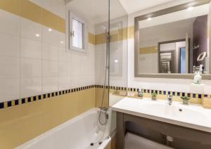 łazienka z umywalką, wanną i lustrem w obiekcie Hôtel du Golf de Pont Royal - appartement paisible rez de jardin - terrasse & piscine w mieście Mallemort