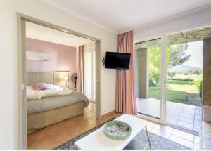 sypialnia z łóżkiem i przesuwanymi szklanymi drzwiami w obiekcie Hôtel du Golf de Pont Royal - appartement paisible rez de jardin - terrasse & piscine w mieście Mallemort