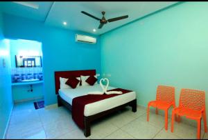 a blue bedroom with a bed and two orange chairs at Paradise Mystic Tones in Auroville