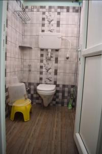 a small bathroom with a toilet and a yellow stool at Paradise Mystic Tones in Auroville