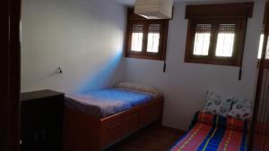 a small bedroom with a bed and two windows at Apartamento Camarena de la Sierra in Camarena de la Sierra