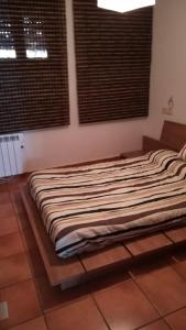 a bed sitting in a room with two windows at Apartamento Camarena de la Sierra in Camarena de la Sierra