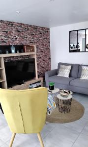 a living room with a yellow chair and a couch at La petite ruette in Le Molay-Littry