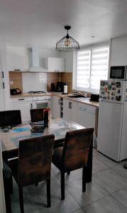 a kitchen with a table and chairs and a refrigerator at La petite ruette in Le Molay-Littry