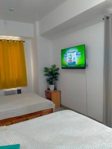 une chambre avec deux lits et une télévision au mur dans l'établissement Sea Residences Ace, à Manille