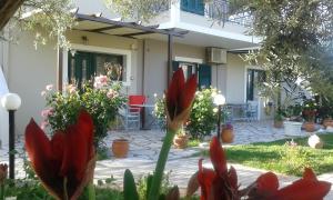 une maison avec des fleurs rouges dans la cour avant dans l'établissement Danai, à Tsoukaladhes