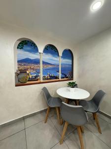 tavolo e sedie in una stanza con tre finestre di Il rifugio di Kekka a Napoli
