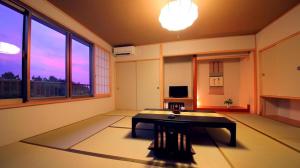 a living room with a table and a large window at Kuju Kanko Hotel in Kokonoe
