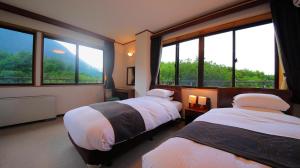 two beds in a room with large windows at Kuju Kanko Hotel in Kokonoe +117 photos