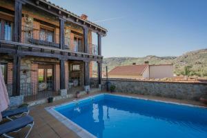 une maison avec une piscine à côté d'un bâtiment dans l'établissement Casa rural Las Eras de Riofrio, à Ríofrío