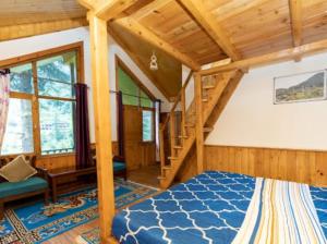ein Schlafzimmer mit einem blauen Bett in einem Holzhaus in der Unterkunft Majestic View Cottages in Jibhi