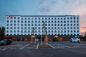 a large white building with a parking lot at ibis Hotel Berlin Airport in Berlin