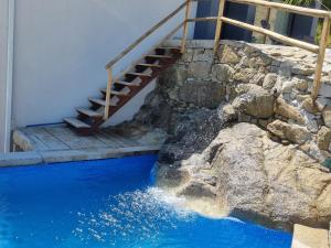 a swimming pool with a staircase next to a stone wall at Felicidade in Mondim de Basto