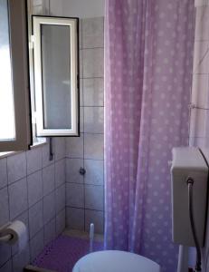 a bathroom with a purple shower curtain and a toilet at Casa Marina Maltese via ucca marina SANTA MARIA DEL FOCALLO ISPICA in Santa Maria Del Focallo
