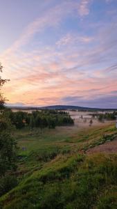a grassy field with a field with fog in the distance at Kuttainen Lodge in Karesuando