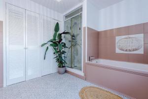 Un baño con bañera y una planta en maceta. en Ascot House, en Buxton 178 fotos más