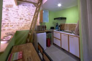 a small kitchen with green walls and a ladder at Le ptit refuge in Annezay